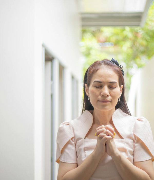 Woman meditating with a serene expression against a sand-colored background.